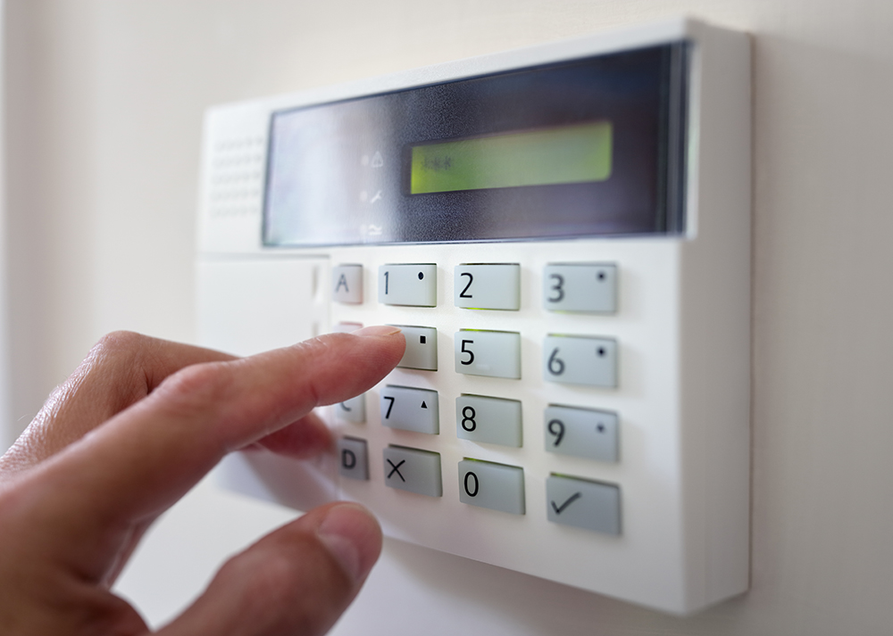 alarm keypad on a wall with persons hand